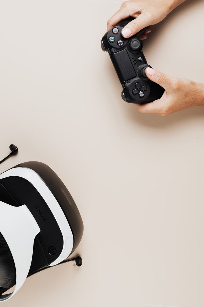 Flat lay of VR headset and gaming controller on a beige background.
