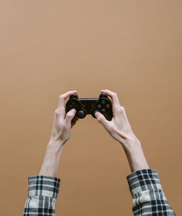 Close-up of hands holding a video game controller against a brown checkered background.