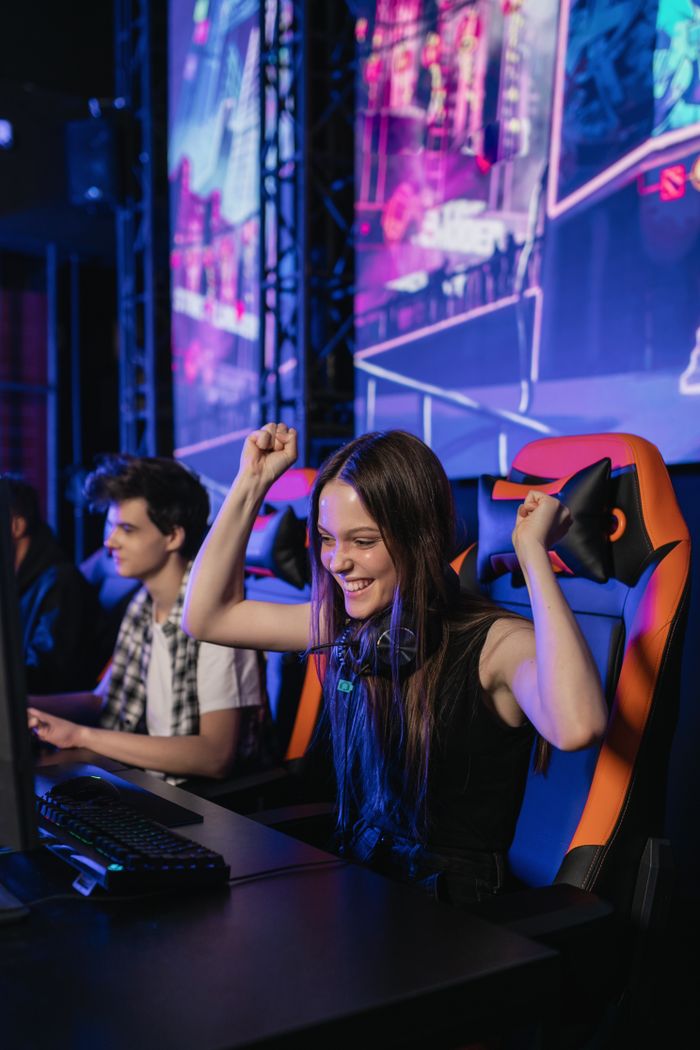 Young woman celebrating a win while playing video games at an esports event.